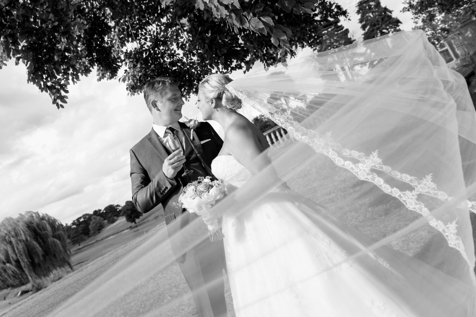 Wedding_Photography___Bride_and_Groom_Kissing_by_the_Lake_with_Veil_Swept_by_the_Wind_in_Black_and_White__Brocket_Hall__Welwyn__Hertfordshire___Talissa_Fernando_Photography_1512677025